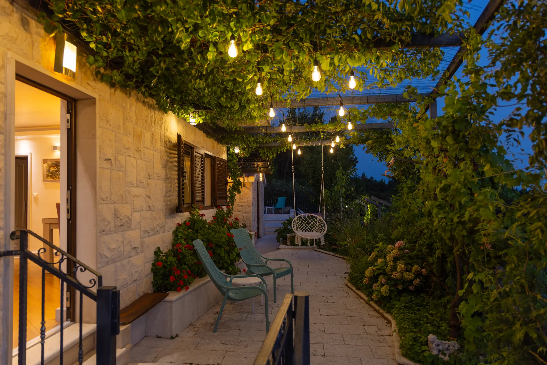 Illuminated vine-covered terrace at Villa Keti after sunset